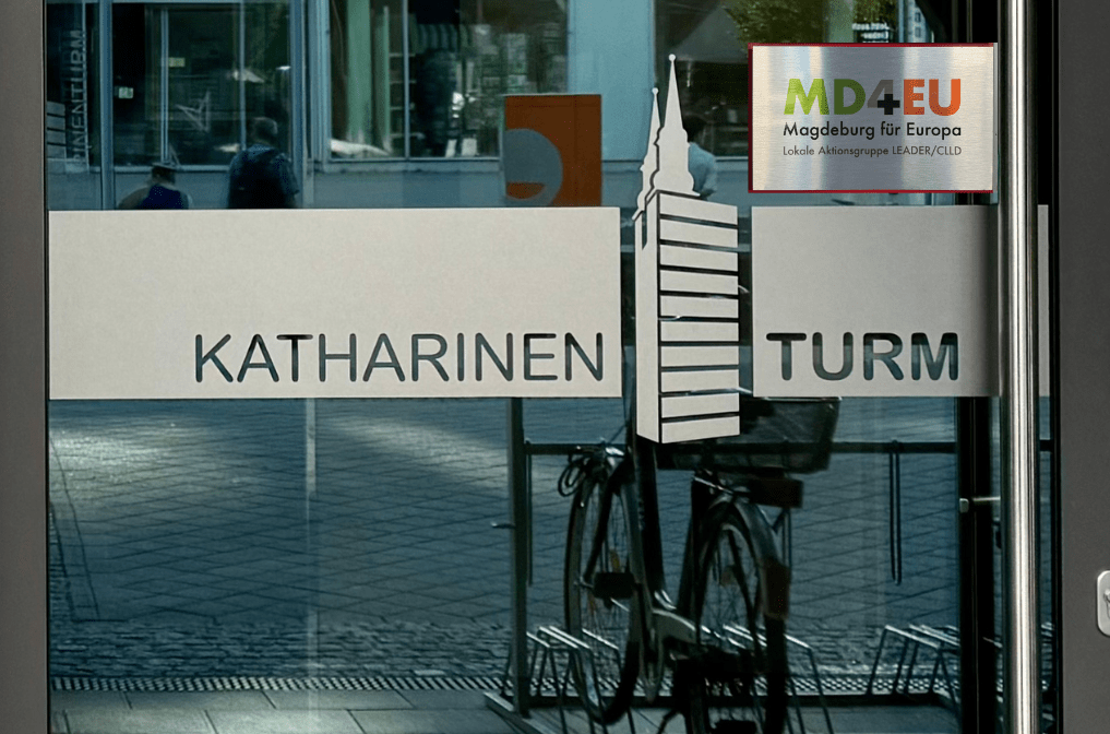 Foto von der Glas-Eingangstür mit Schriftzug Katharinenturm, rechts oben Logo der LAG Magdeburg für Europa