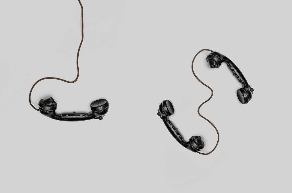 3 schwarze Telefone mit Schnur auf hellgrauem Hintergrund